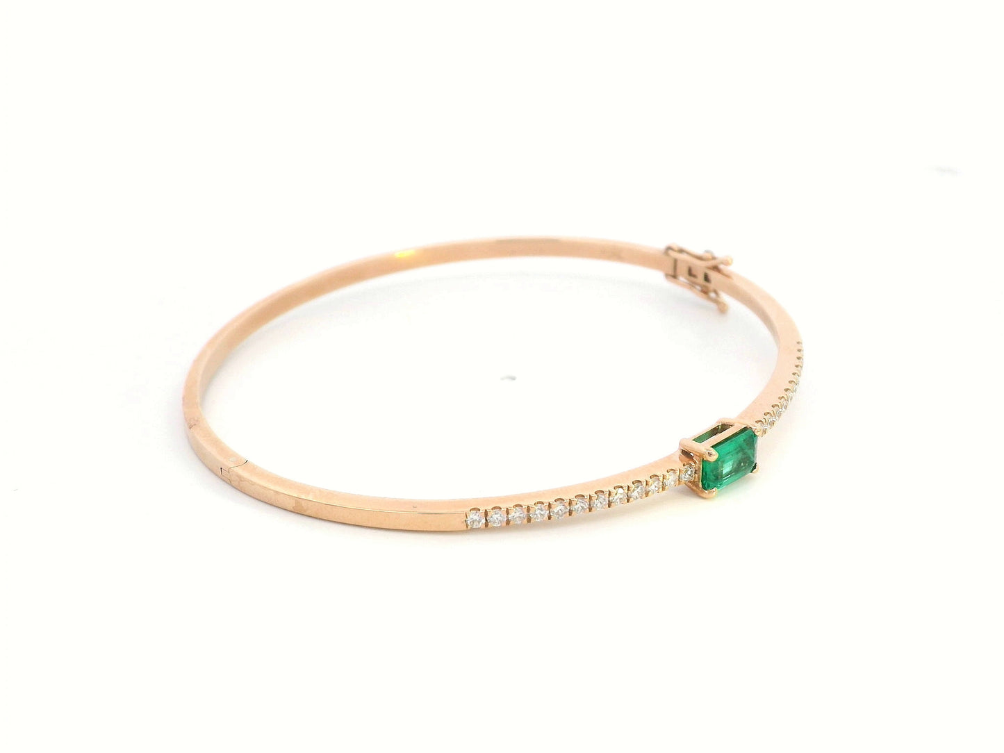 18K gold bangle with emerald-cut 0.50 carat green emerald and 0.34 carat round diamonds in a hinged bracelet design.