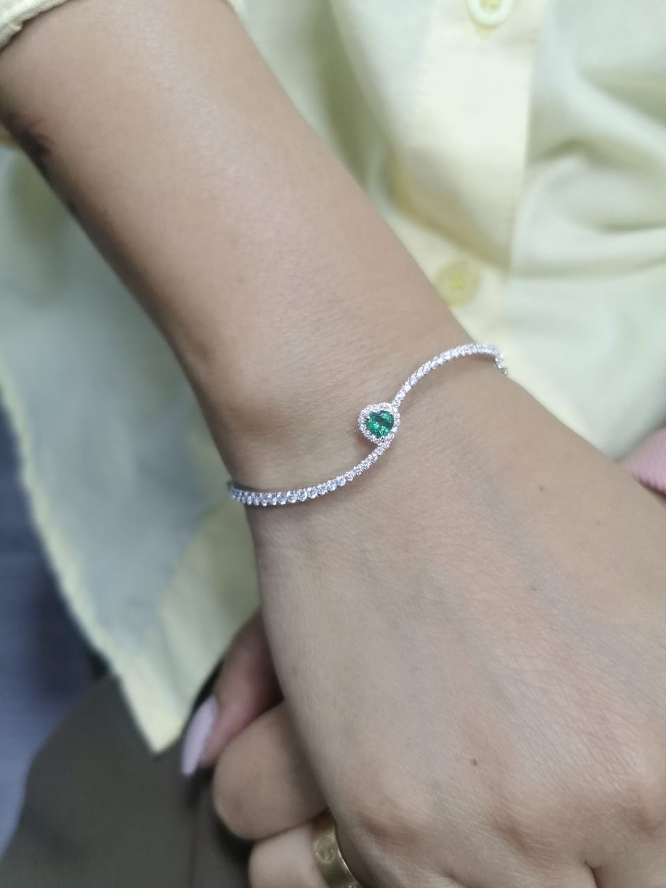 18K white gold bangle with heart-shaped emerald and pavé diamonds, elegant curved design