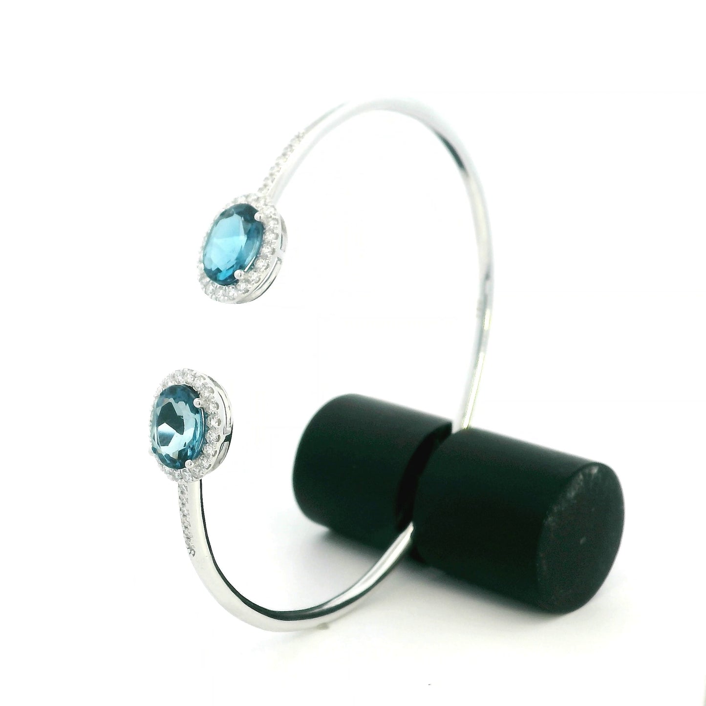 18K white gold open cuff bangle featuring two oval natural London Blue Topaz gemstones totaling 4.21 carats, surrounded by natural diamond halos totaling 0.57 carat.
