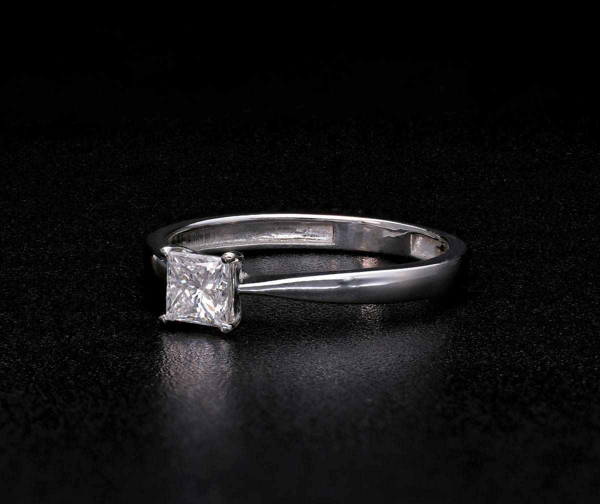 Princess cut diamond solitaire engagement ring in 18K white gold featuring a square diamond in a four-prong setting with a polished band.