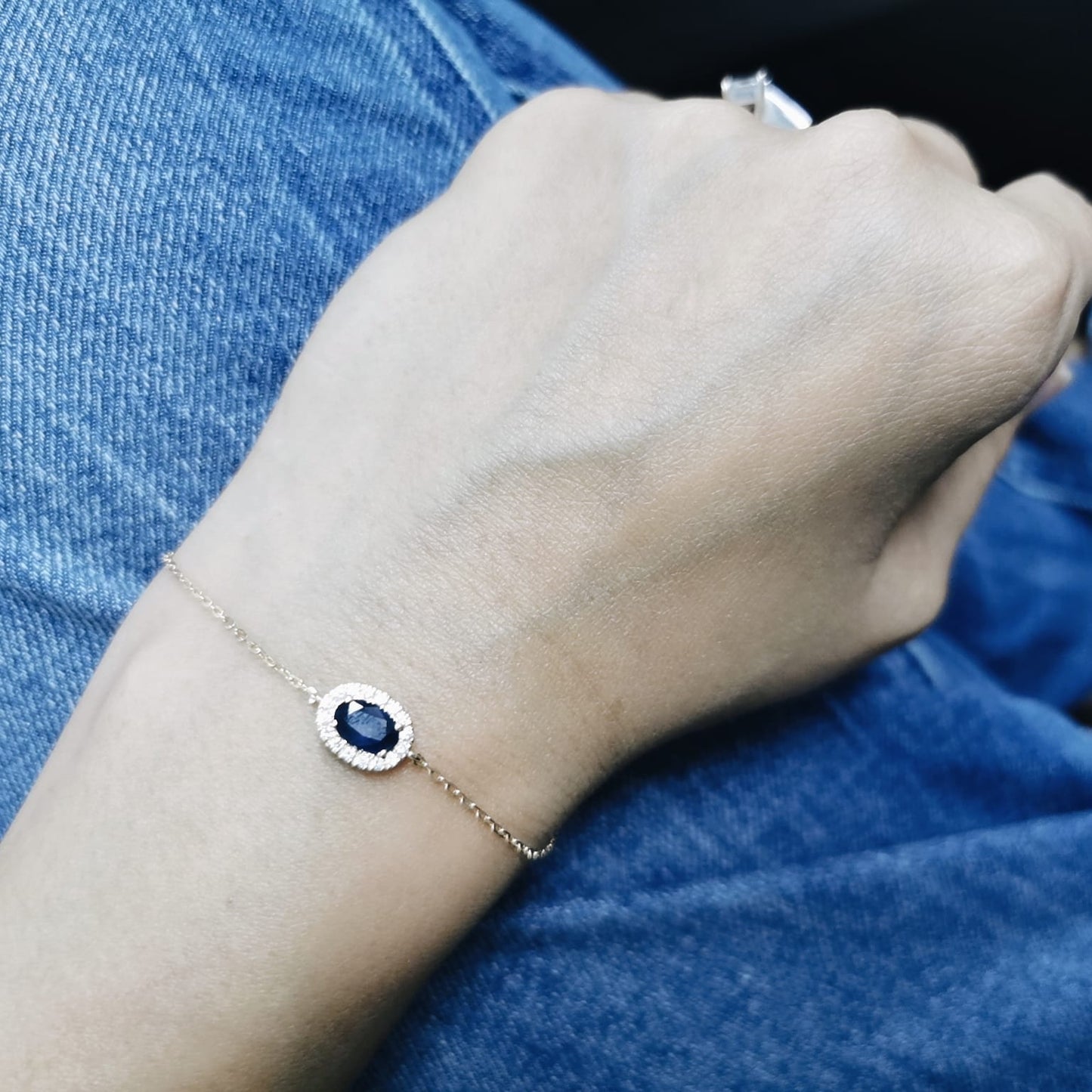 18K yellow gold bracelet with oval blue sapphire and round diamond halo on fine gold chain.