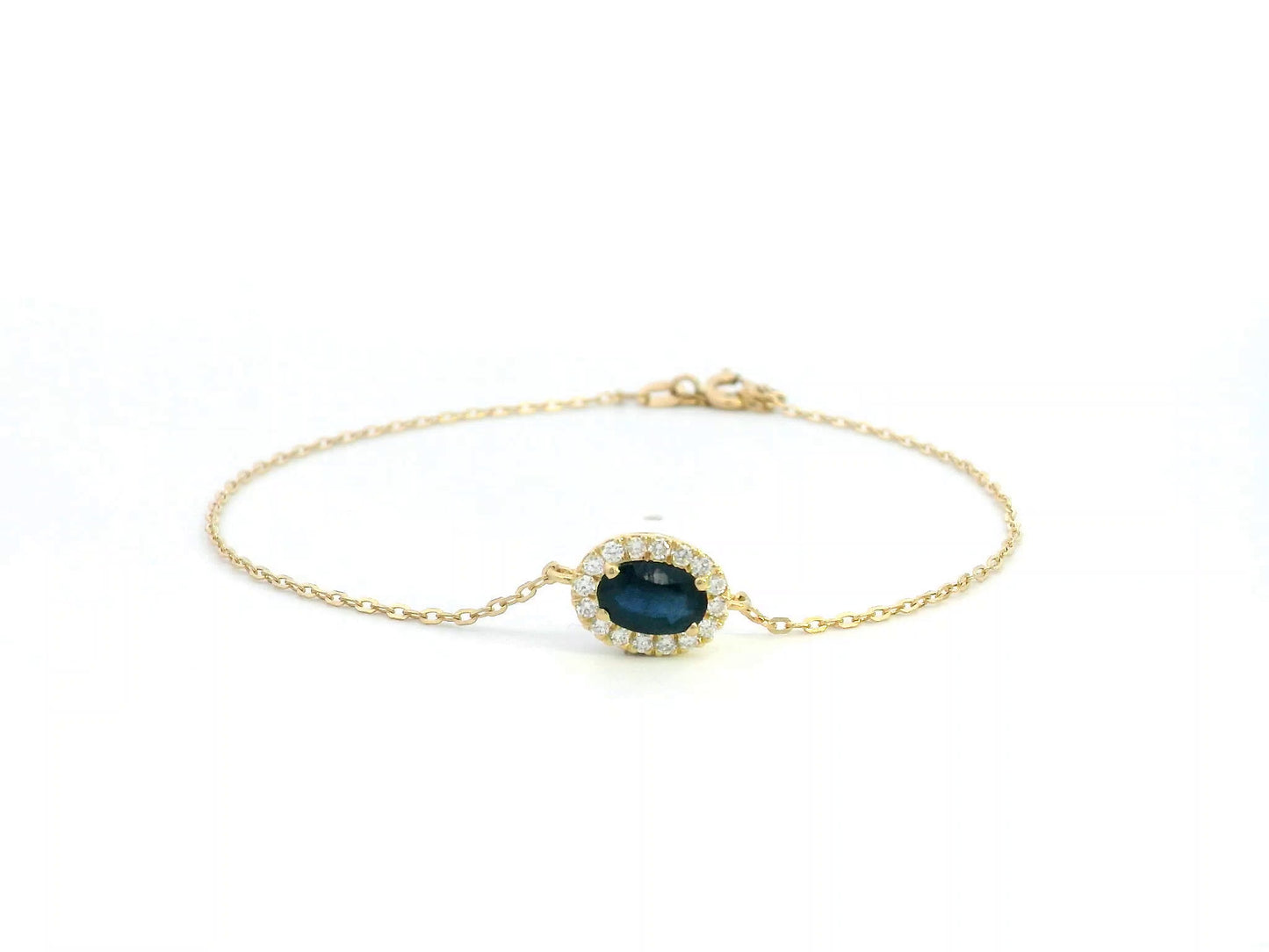 18K yellow gold bracelet with oval blue sapphire and round diamond halo on fine gold chain.