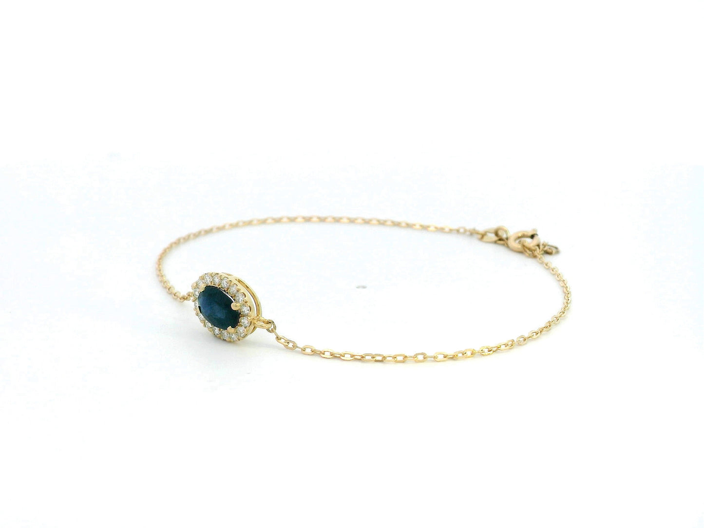 18K yellow gold bracelet with oval blue sapphire and round diamond halo on fine gold chain.