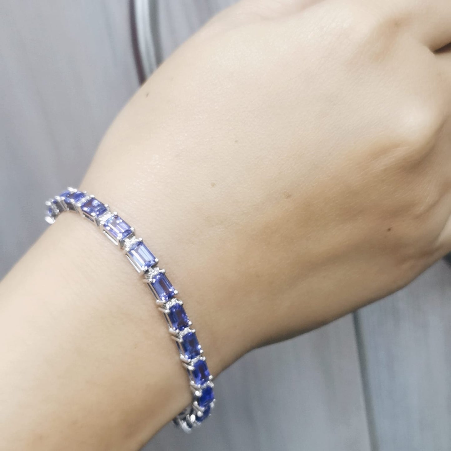 Blue gemstone bracelet on a wrist with a neutral background
