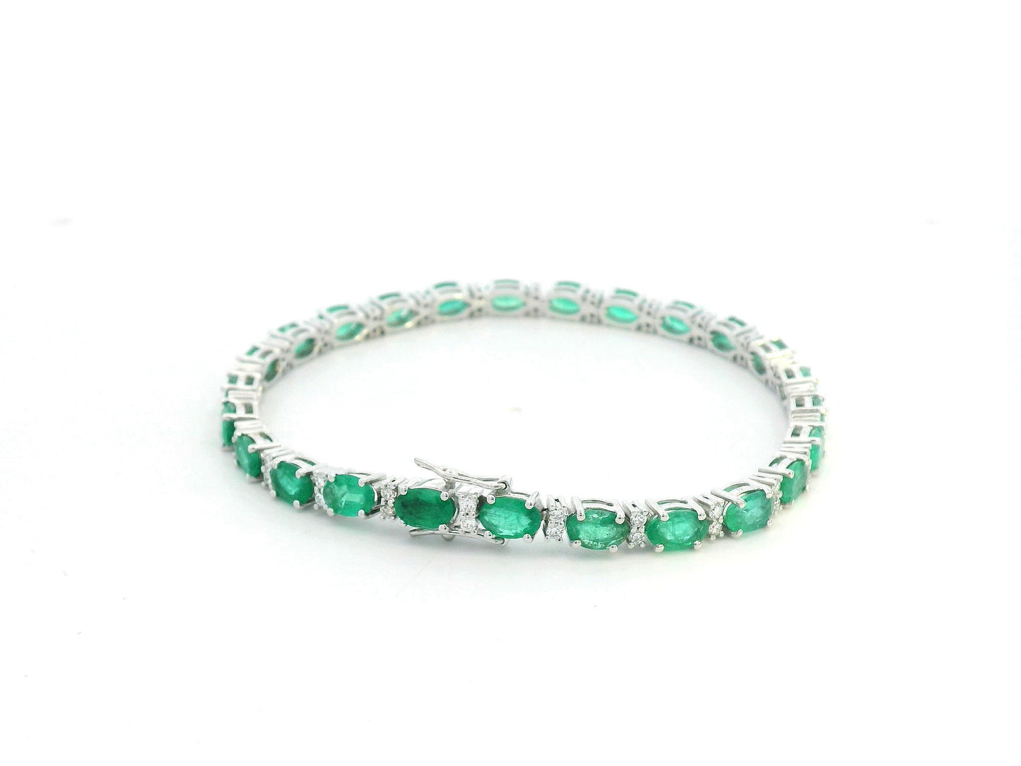 18K white gold tennis bracelet with 8.88ct oval-cut emeralds and 0.80ct diamond accents.