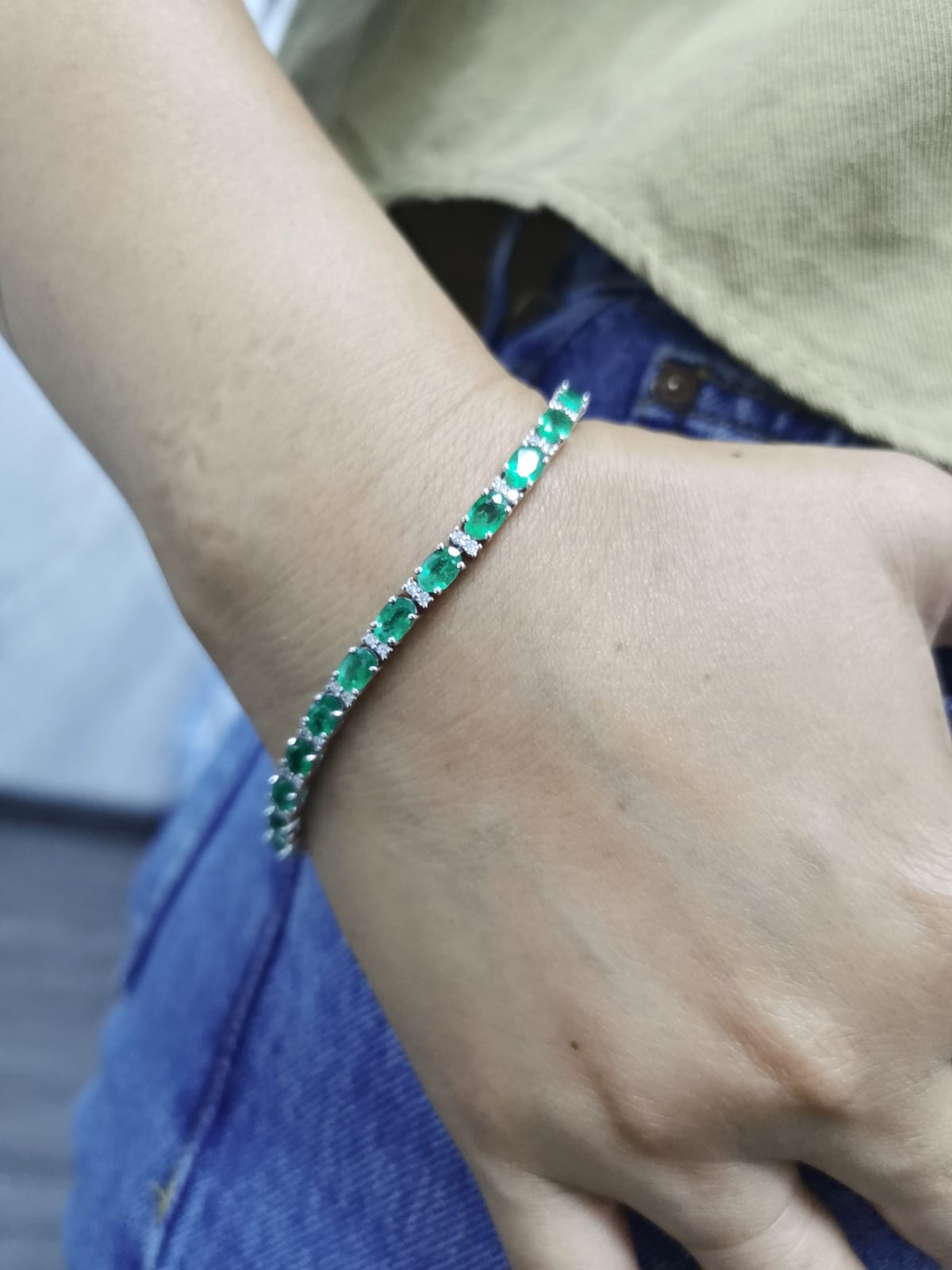 18K white gold tennis bracelet with 8.88ct oval-cut emeralds and 0.80ct diamond accents.