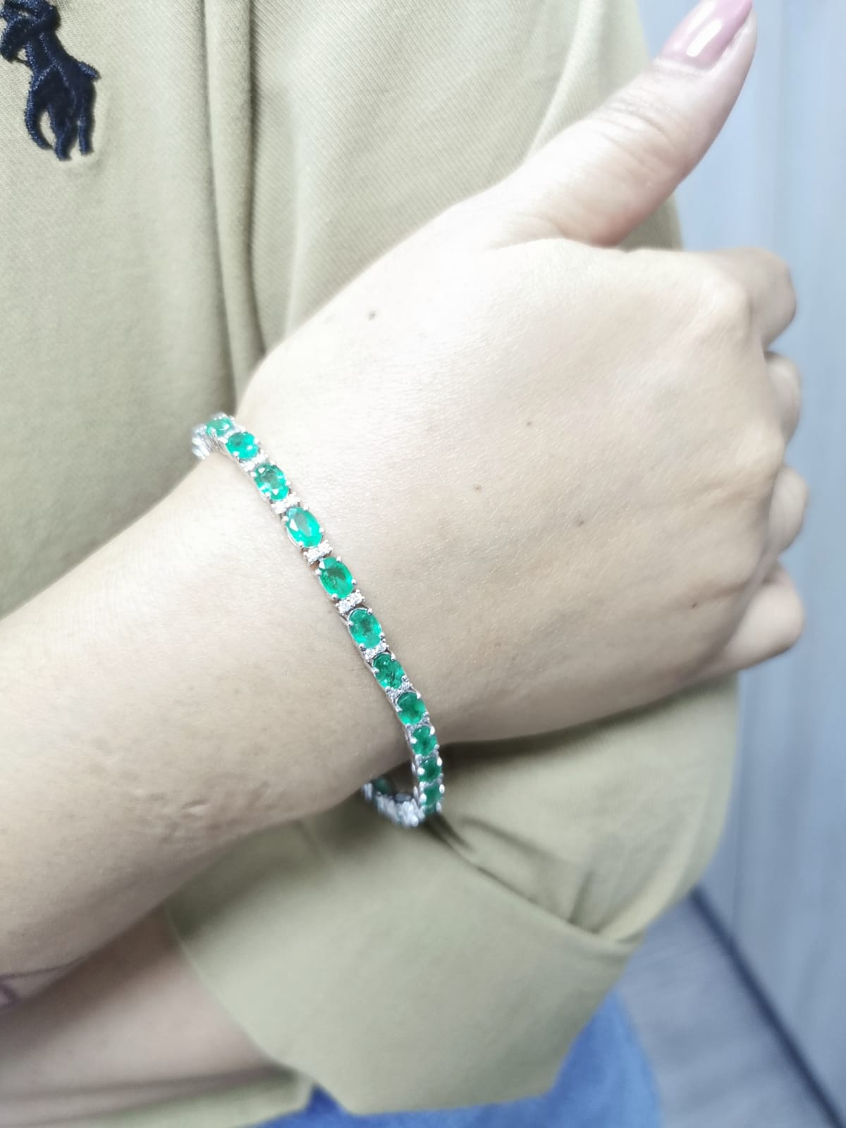 18K white gold tennis bracelet with 8.88ct oval-cut emeralds and 0.80ct diamond accents.