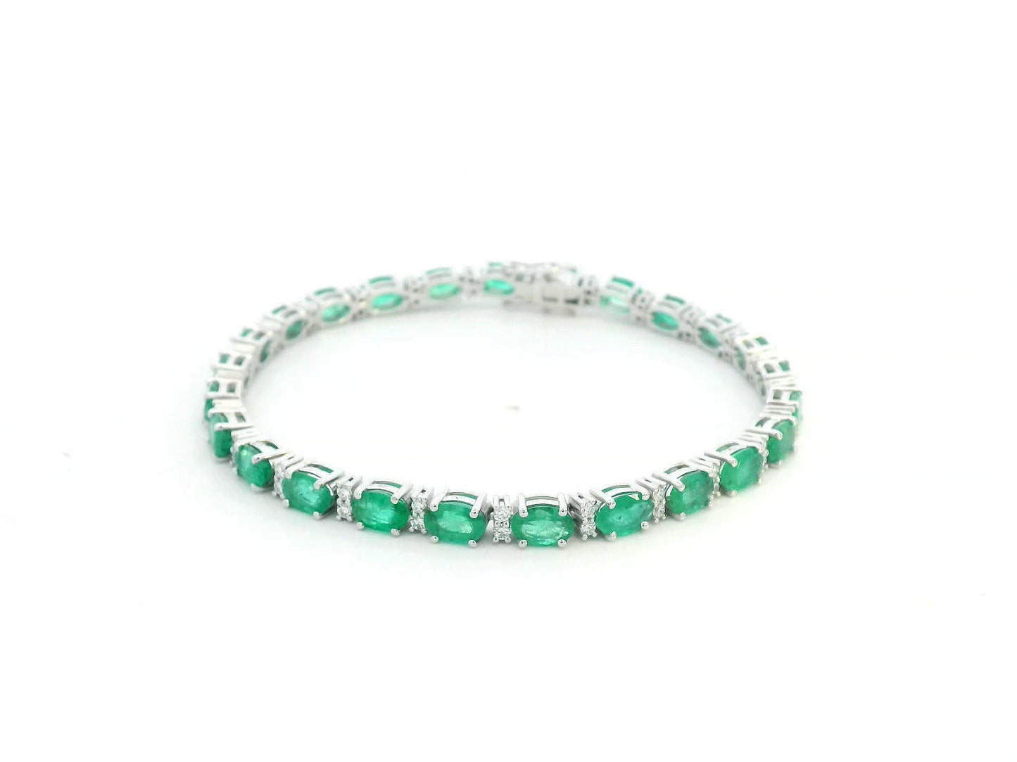 18K white gold tennis bracelet with 8.88ct oval-cut emeralds and 0.80ct diamond accents.