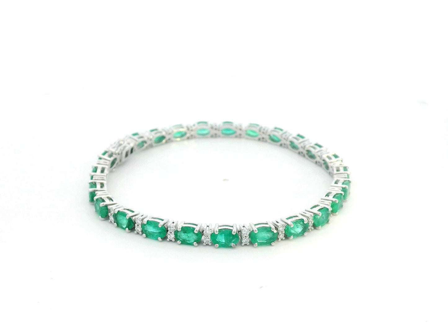 18K white gold tennis bracelet with 8.88ct oval-cut emeralds and 0.80ct diamond accents.