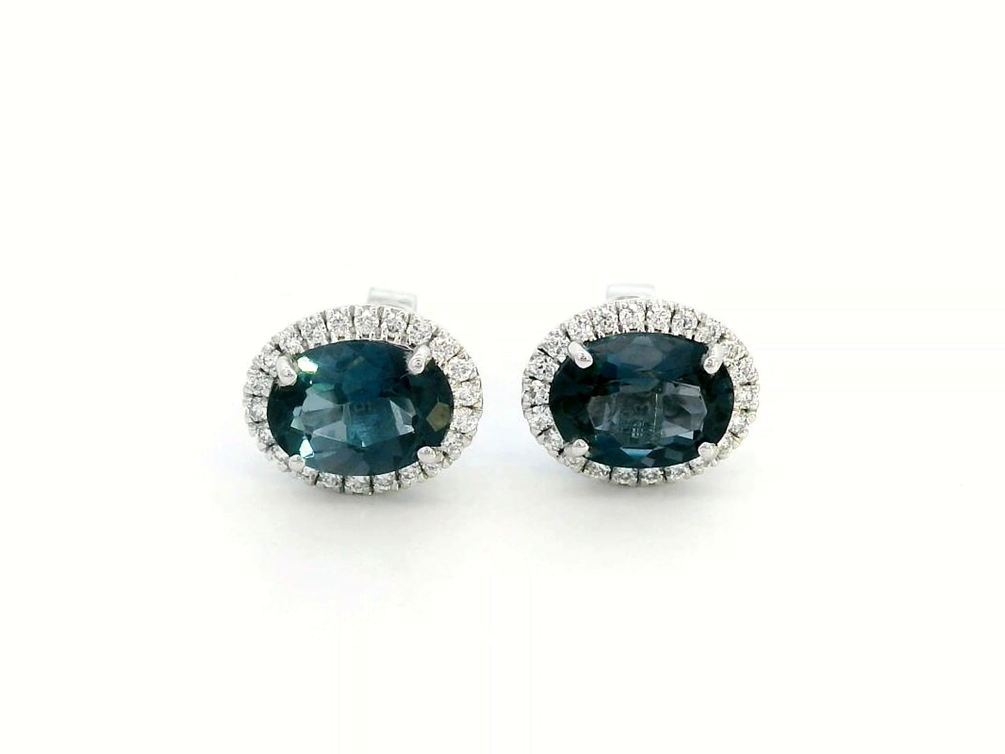 18K gold stud earrings featuring 2.90 carats of oval London Blue Topaz, encircled by a 0.25-carat diamond halo. Classic elegance with secure push-back closure.