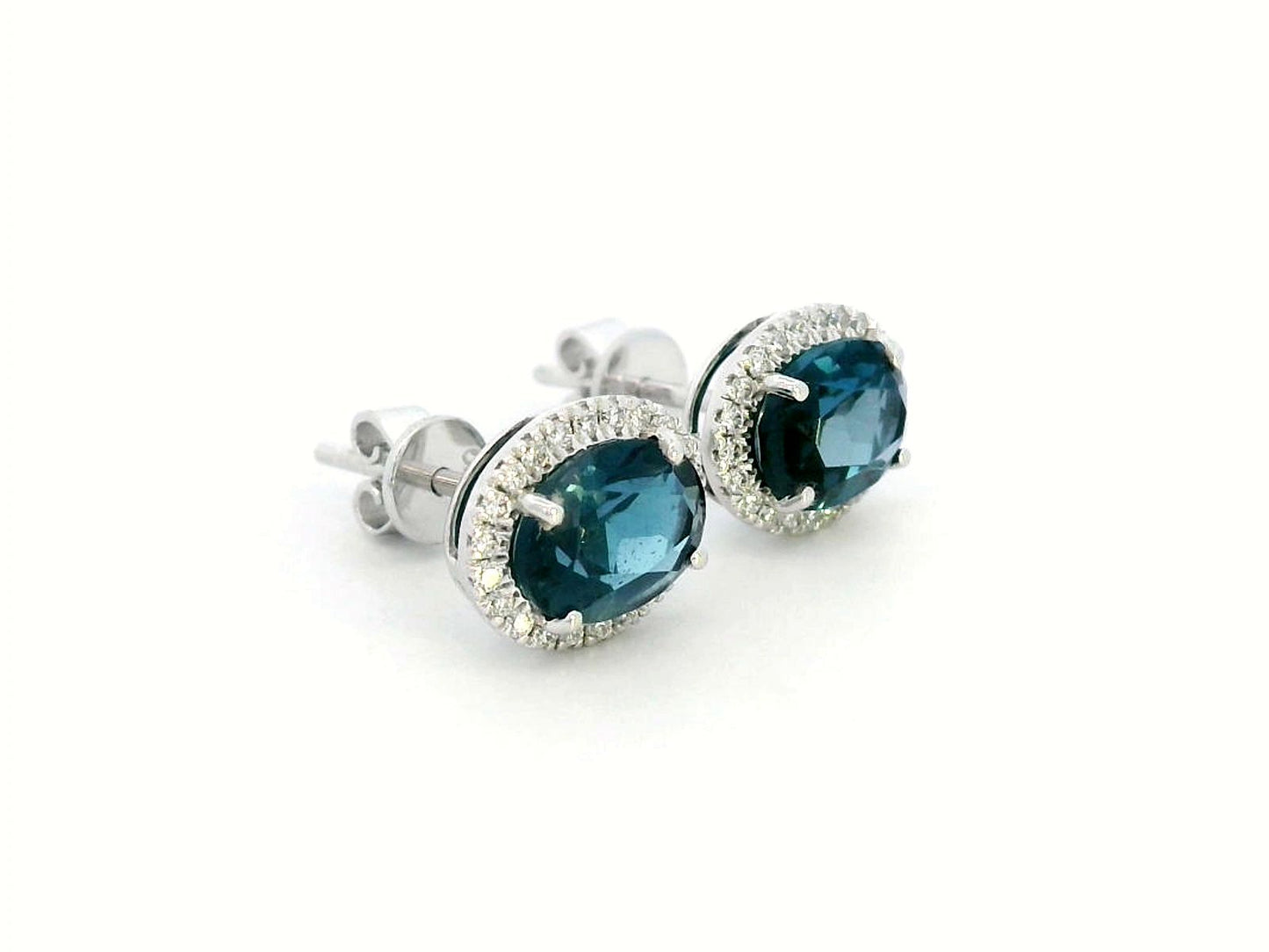 18K gold stud earrings featuring 2.90 carats of oval London Blue Topaz, encircled by a 0.25-carat diamond halo. Classic elegance with secure push-back closure.