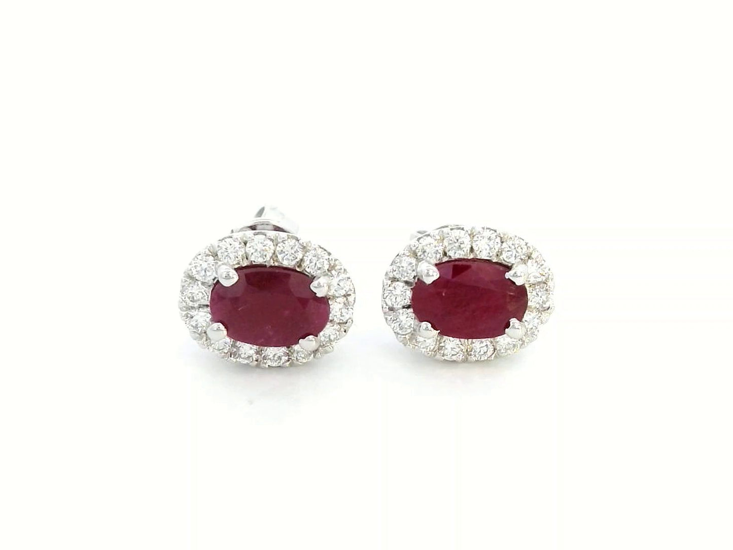 White gold earrings with oval rubies (1.52 CT) and a halo of sparkling diamonds (0.33 CT). Classic and elegant fine jewelry.