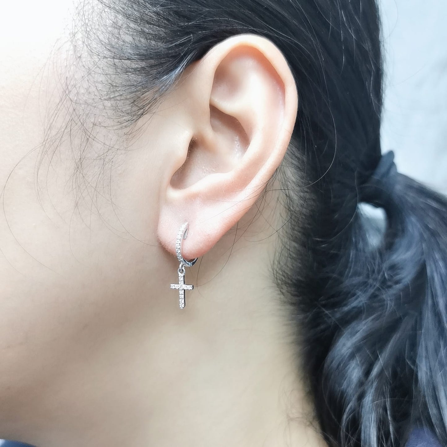 18K gold huggie hoop earrings with a 0.22-carat diamond cross charm, featuring pavé-set diamonds and a secure hinged snap closure. Elegant and meaningful.