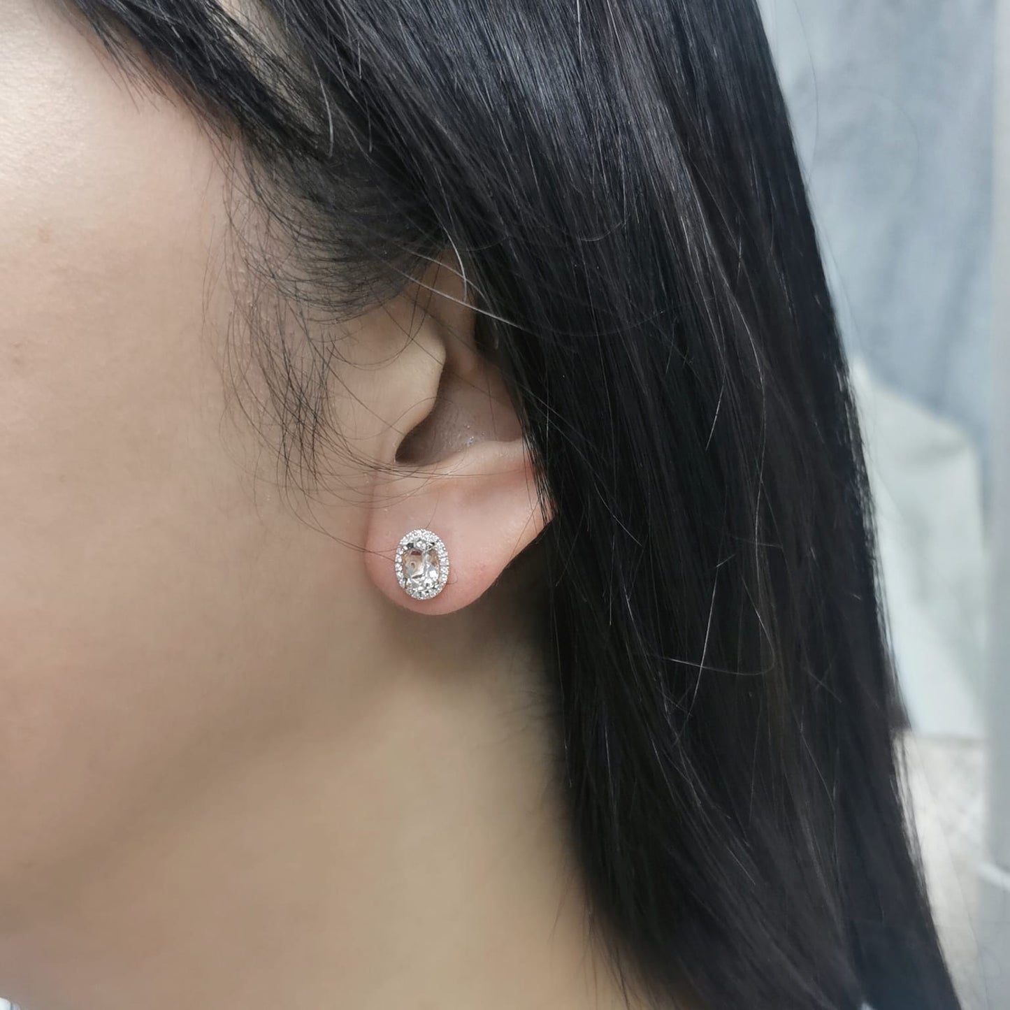 Elegant 18K gold stud earrings featuring 1.40 carats of oval-cut morganite gemstones, each encircled by a halo of 0.19 carats of round diamonds, secured with a push-back closure for timeless sophistication.