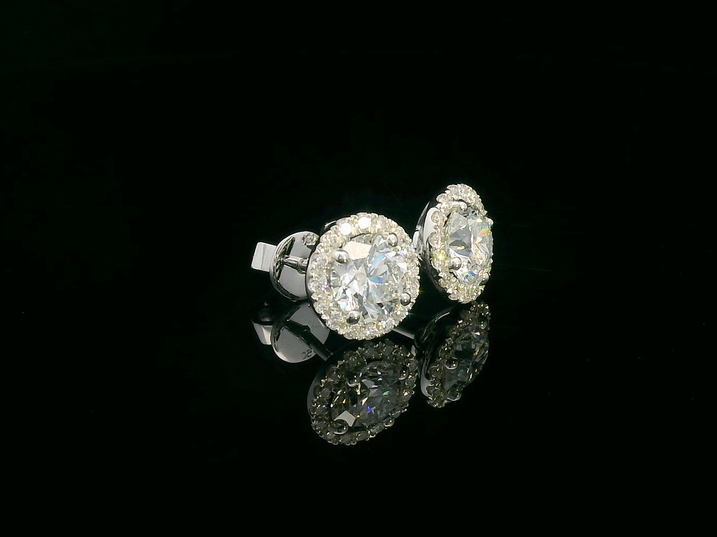 18K gold diamond halo stud earrings featuring two 1.00-carat round-cut center diamonds with a 0.33-carat halo – elegant and timeless bridal jewelry.