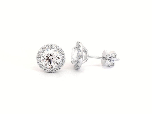 18K gold diamond halo stud earrings featuring two 1.00-carat round-cut center diamonds with a 0.33-carat halo – elegant and timeless bridal jewelry.