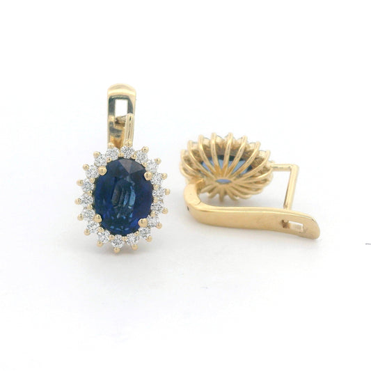 18K gold earrings featuring oval-cut Blue Sapphires (4.36ct) surrounded by a 0.56ct diamond halo, secured with hinged lever-back closures for a comfortable and elegant fit.