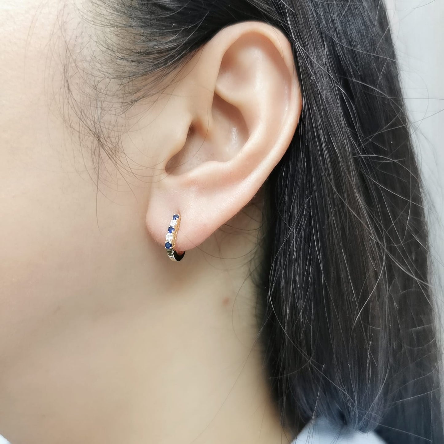18K gold huggie hoop earrings set with deep blue sapphires and diamonds, offering a refined and elegant look.