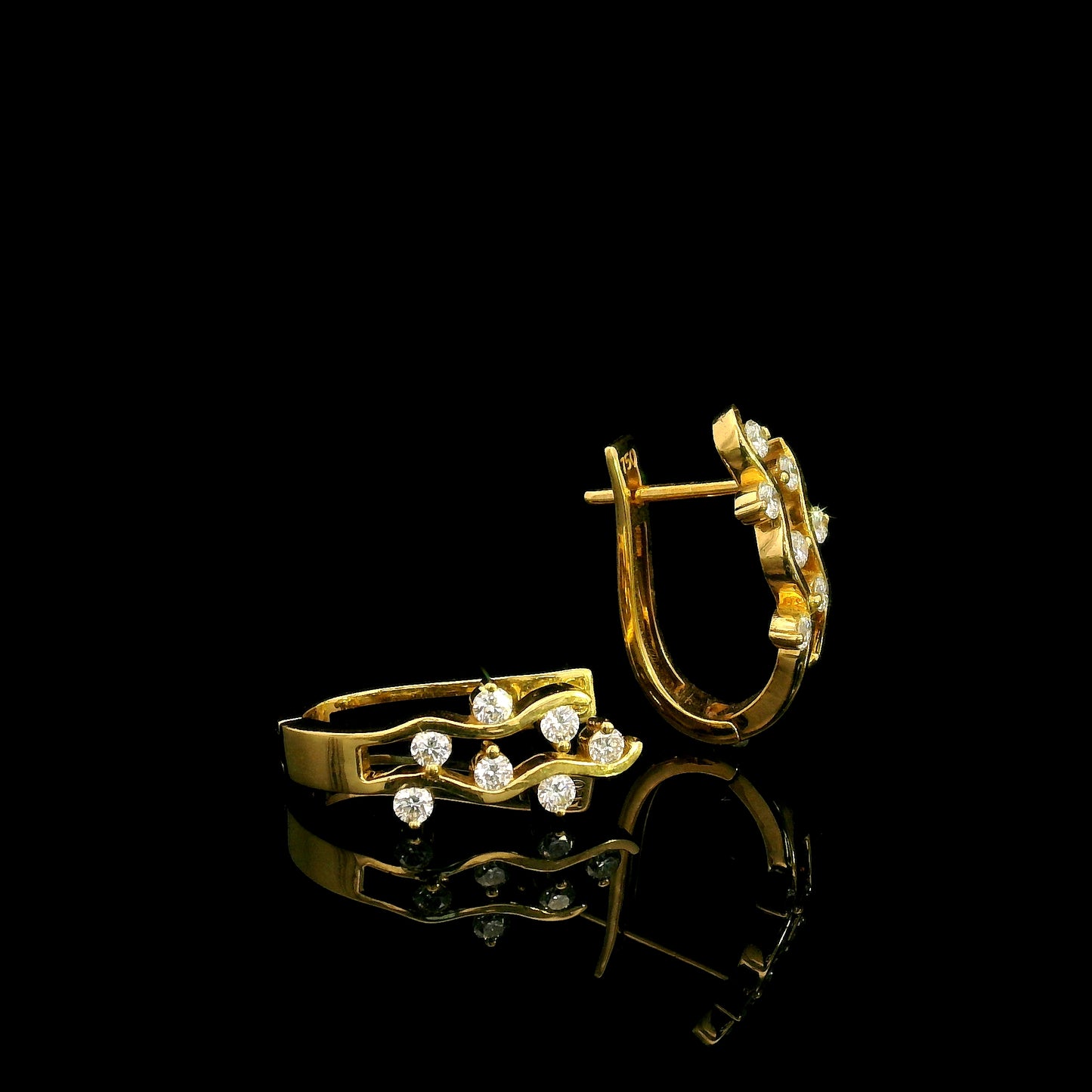 18K yellow gold diamond wave hoop earrings featuring flowing open gold curves with scattered round brilliant diamonds.