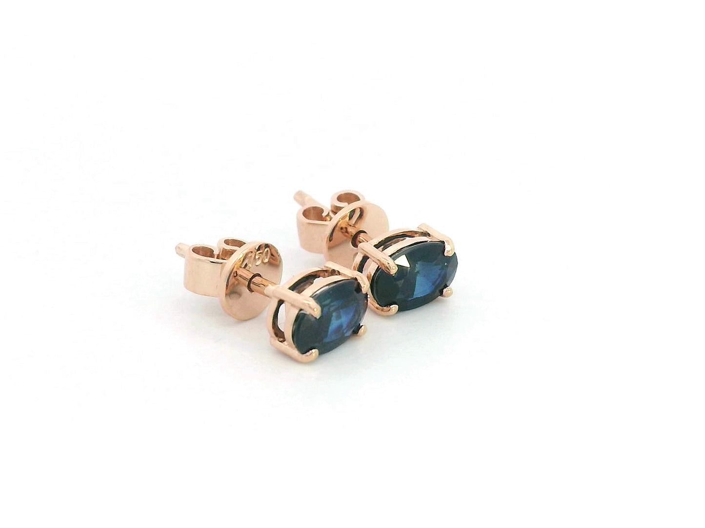 18K rose gold stud earrings with oval-cut natural blue sapphires totaling 1.06 carats, four-prong set with butterfly push backs.