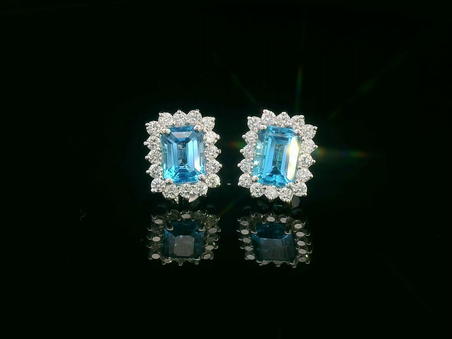 Emerald-cut blue topaz stud earrings framed by a scalloped diamond halo in 18K gold