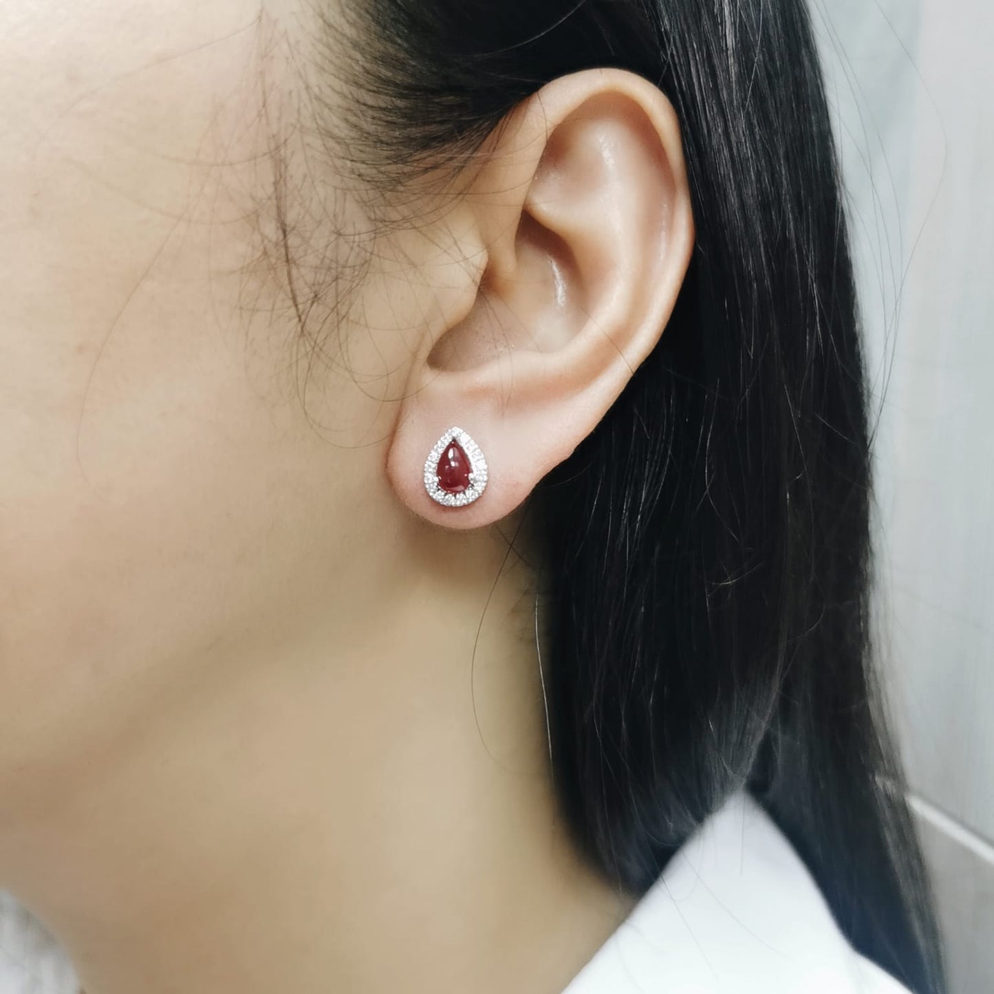 18K gold ruby earrings with pear-shaped 2.21 CT cabochon rubies and diamond halo accents.