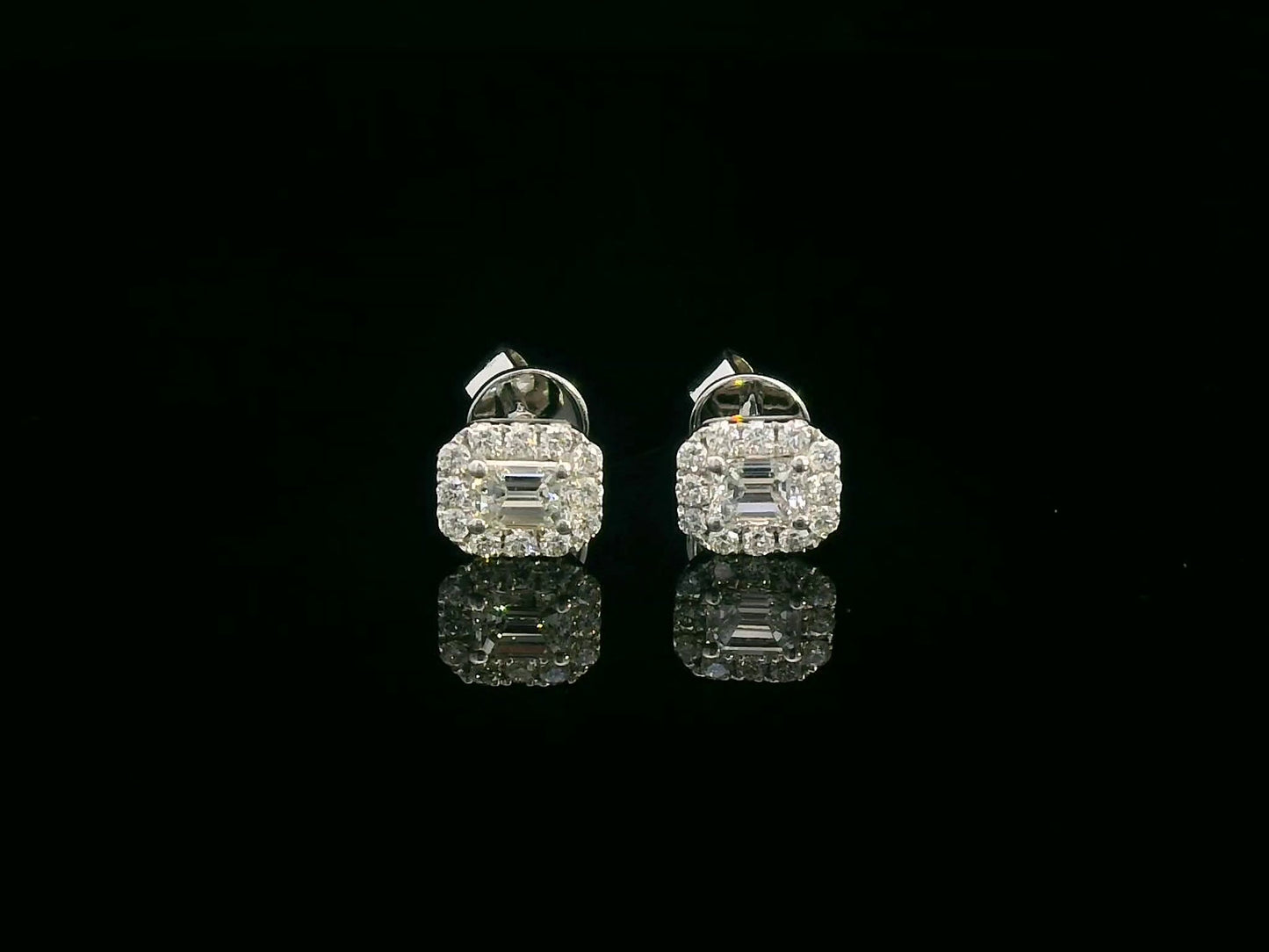 18K gold emerald-cut diamond halo stud earrings with round diamond accents, screw-back style on black background.