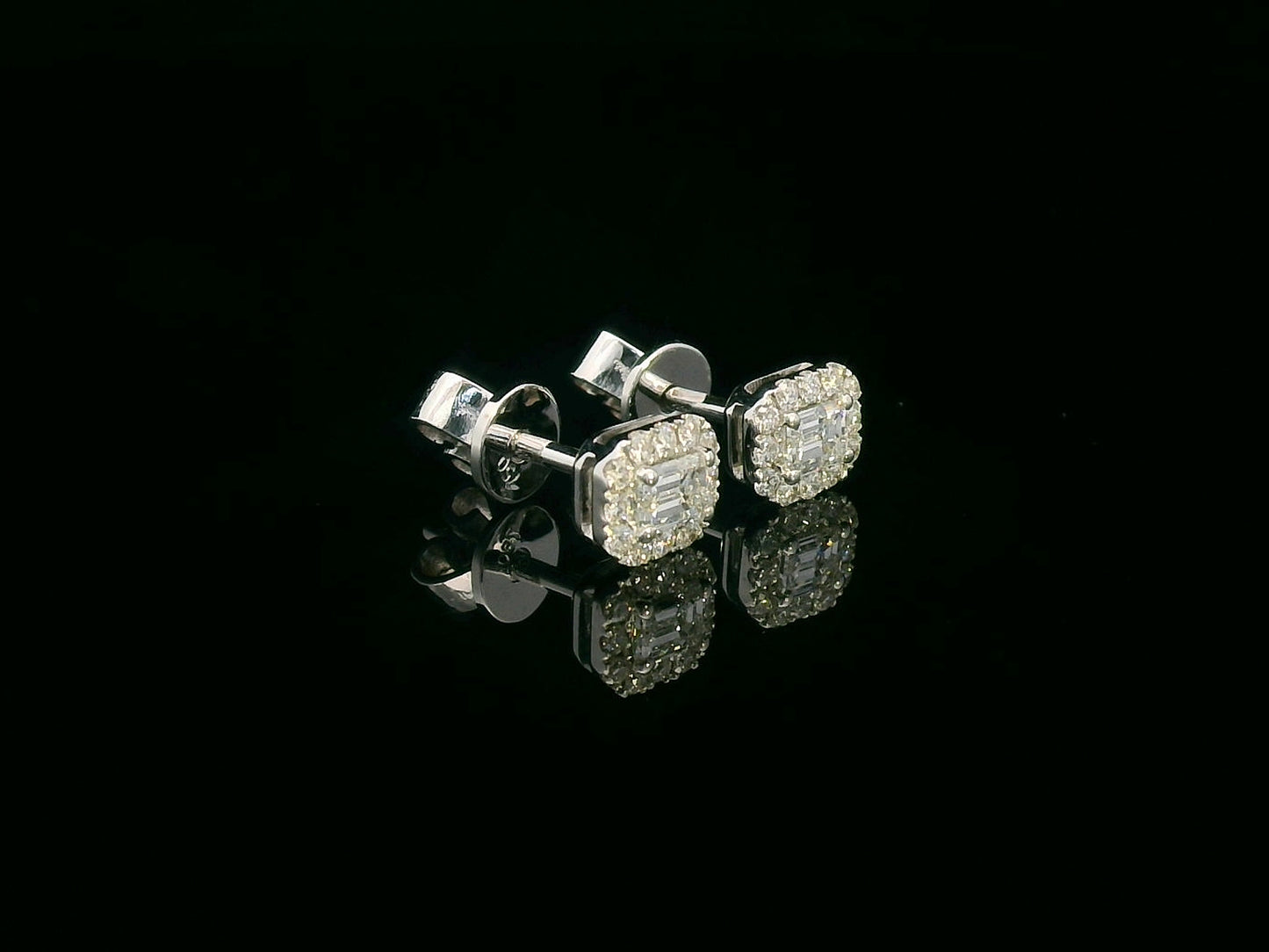 18K gold emerald-cut diamond halo stud earrings with round diamond accents, screw-back style on black background.
