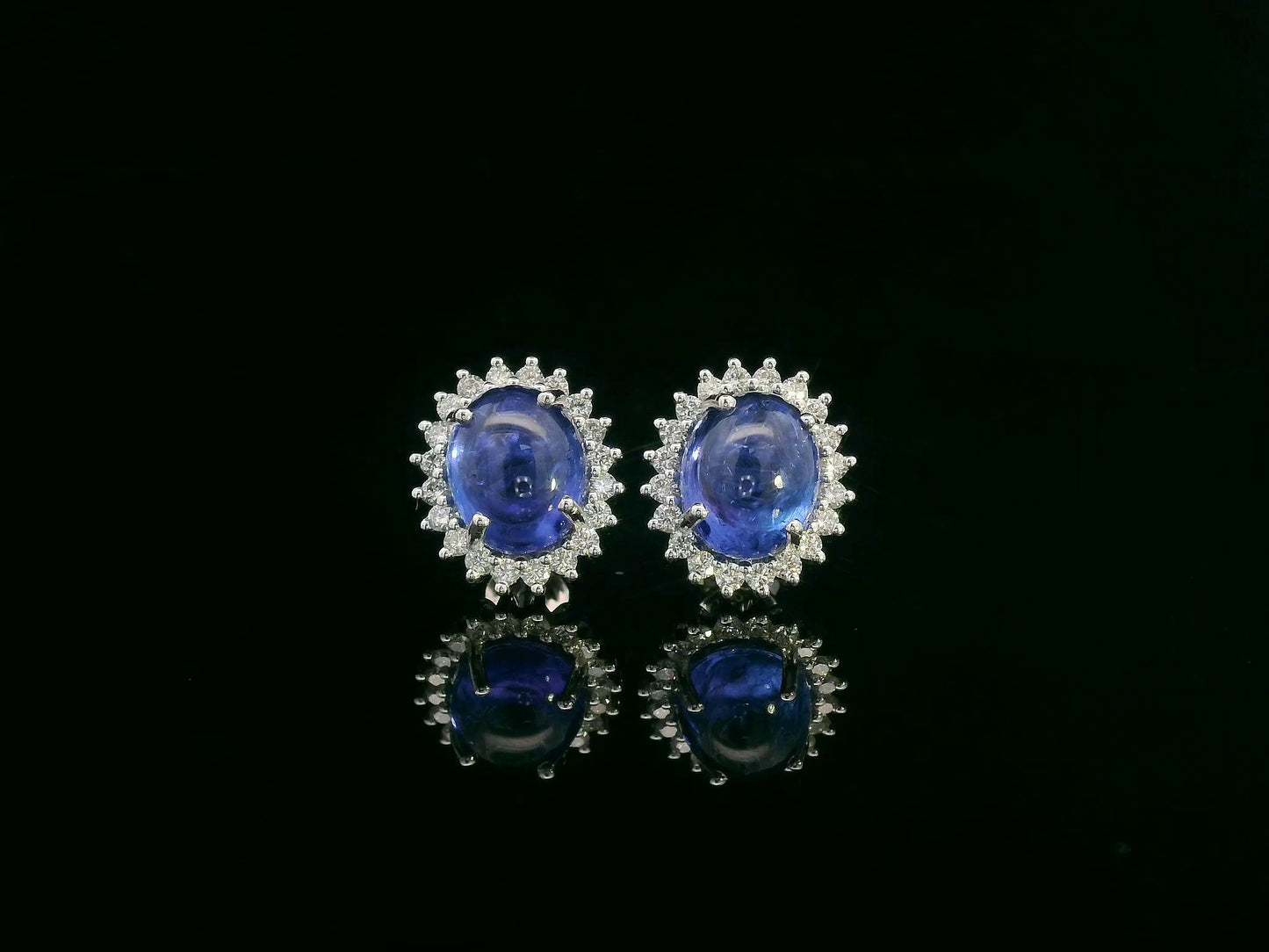 18K gold earrings with oval cabochon Tanzanites and sunburst-style diamond halos totaling 0.70 carats