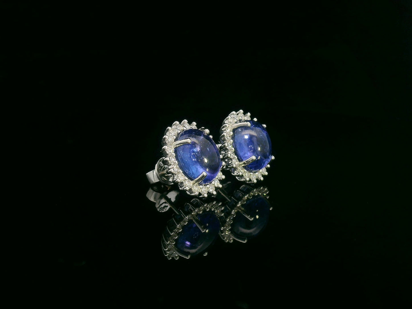 18K gold earrings with oval cabochon Tanzanites and sunburst-style diamond halos totaling 0.70 carats