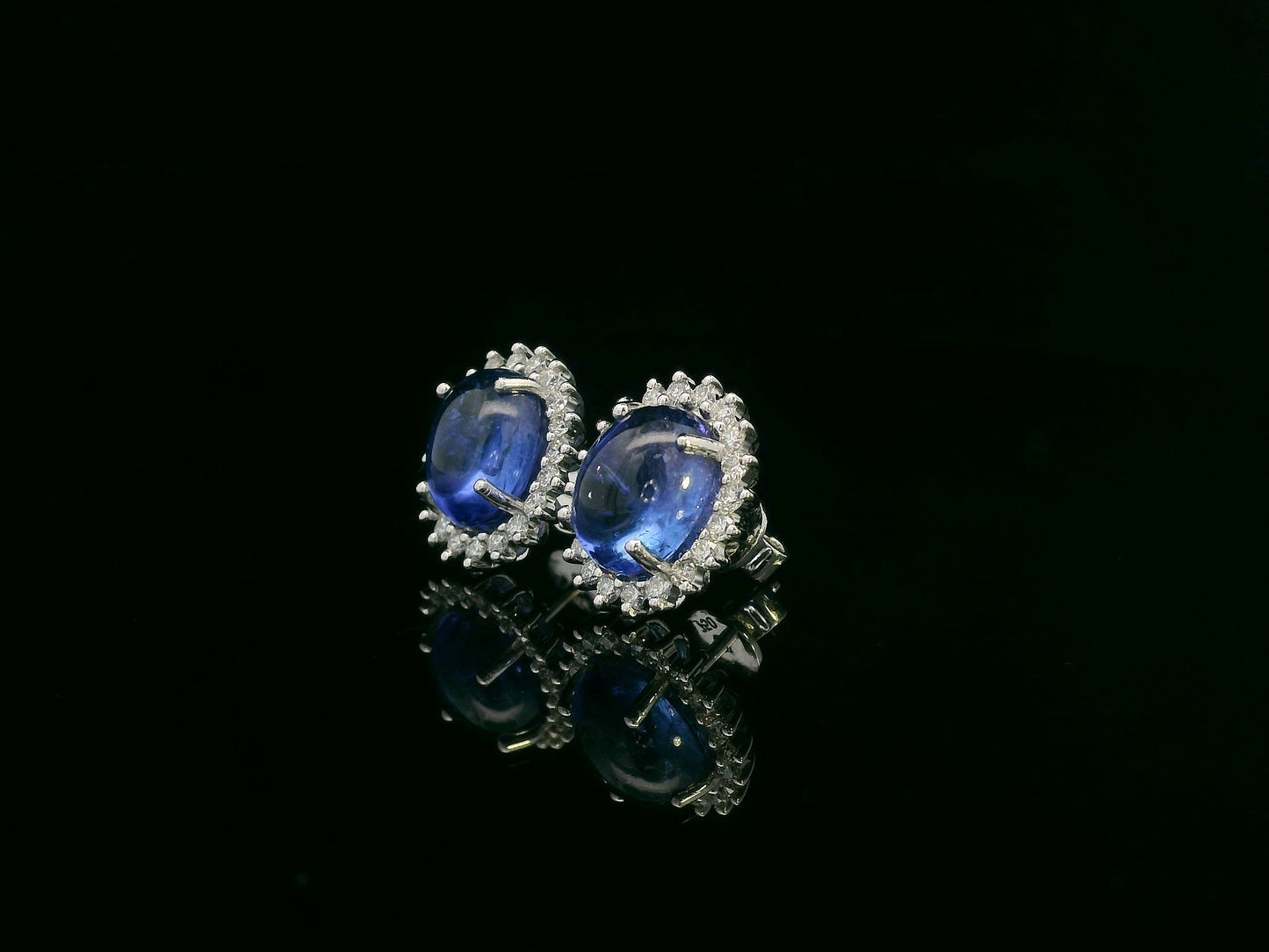 18K gold earrings with oval cabochon Tanzanites and sunburst-style diamond halos totaling 0.70 carats