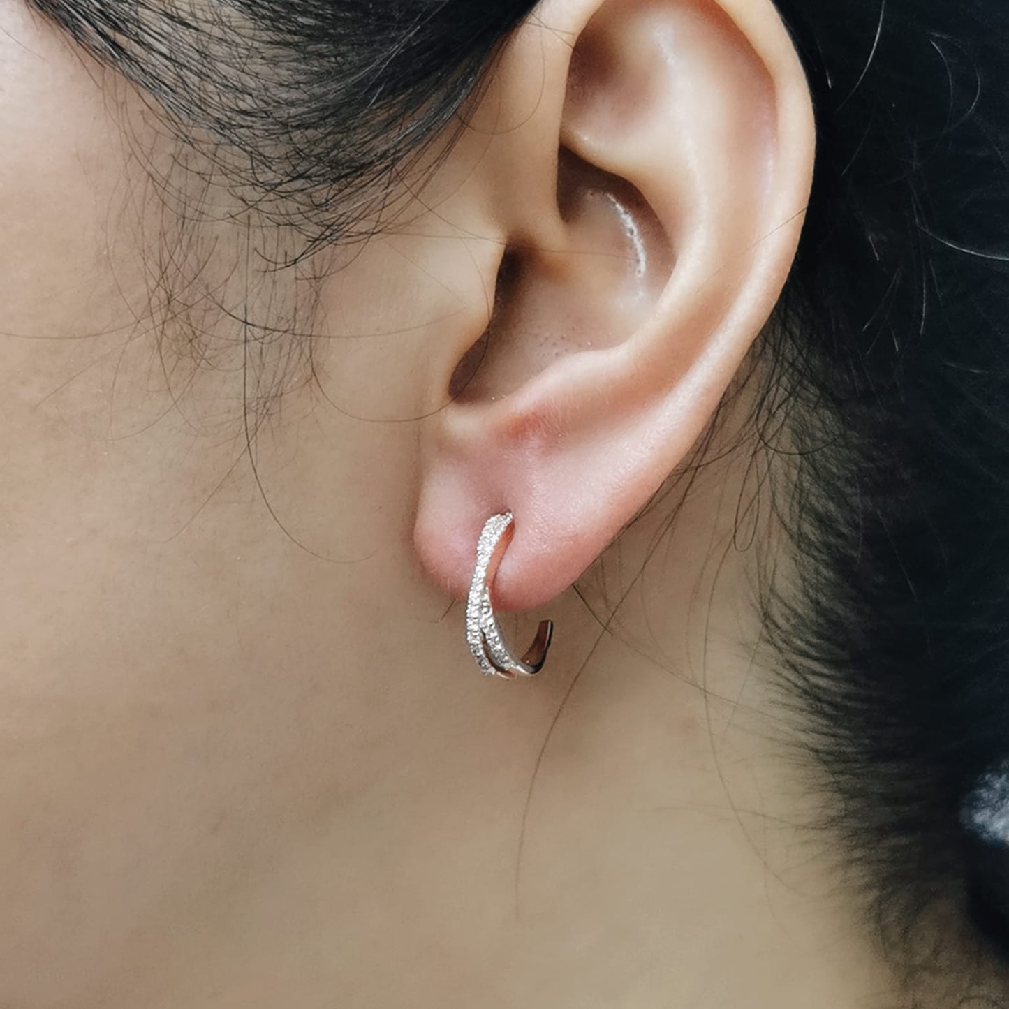 Close-up of an ear wearing a gold and diamond hoop earring