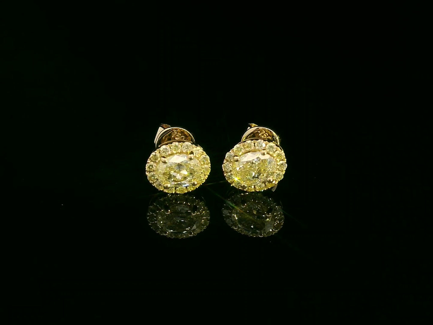 Front view of yellow gold earrings with sparkling fancy yellow diamonds