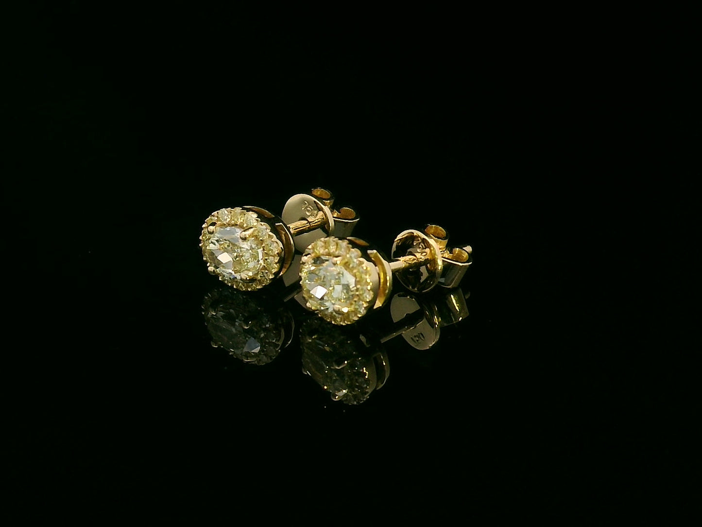 Side view of yellow gold earrings with sparkling fancy yellow diamonds