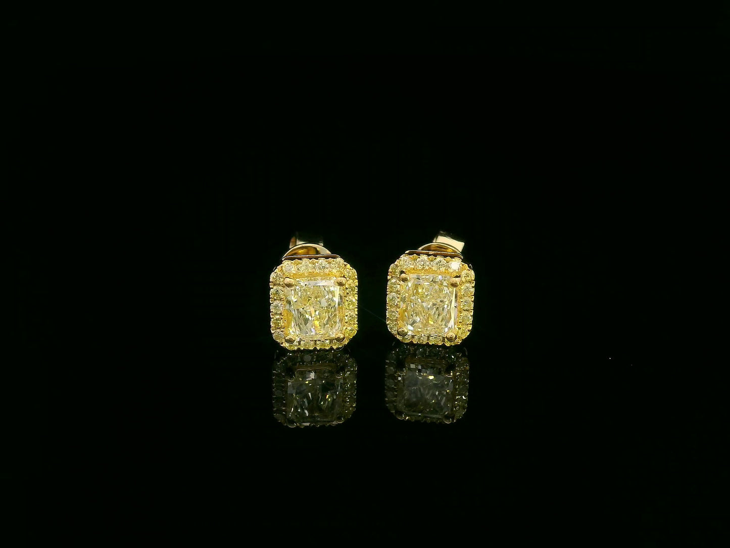 Front view of yellow gold earrings sparkling with radiant-cut fancy yellow diamonds