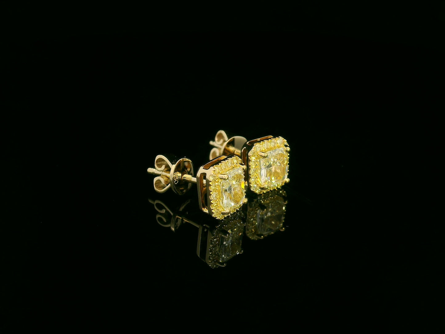 Side view of yellow gold earrings sparkling with radiant-cut fancy yellow diamonds
