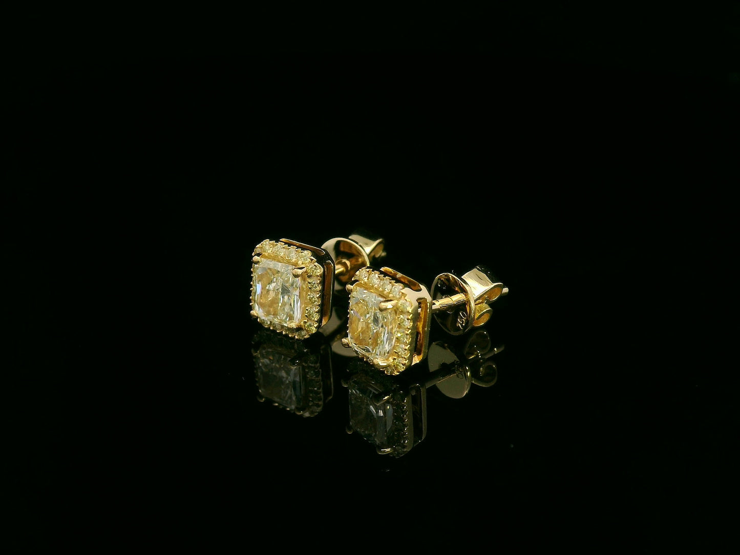 Side view of yellow gold earrings sparkling with radiant-cut fancy yellow diamonds