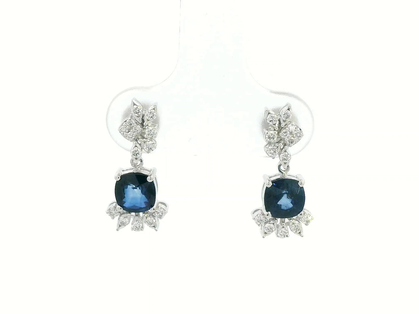 Front view of 18k white gold drop earrings with cushion-cut blue sapphires and diamonds