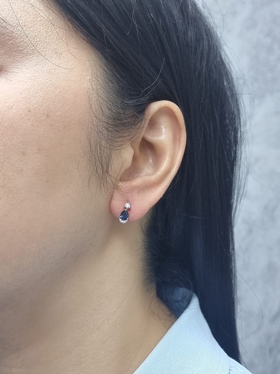 18K white gold drop earrings featuring 0.90ct pear-cut blue sapphires suspended beneath round brilliant diamonds with 0.15ct pavé diamond accent arc.