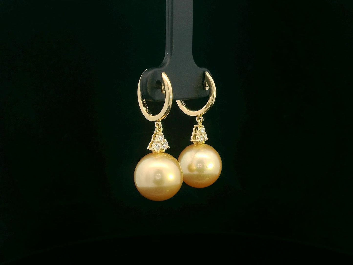 18k yellow gold South Sea pearl earrings featuring golden pearls suspended from hoops with diamond pyramid clusters above each pearl.