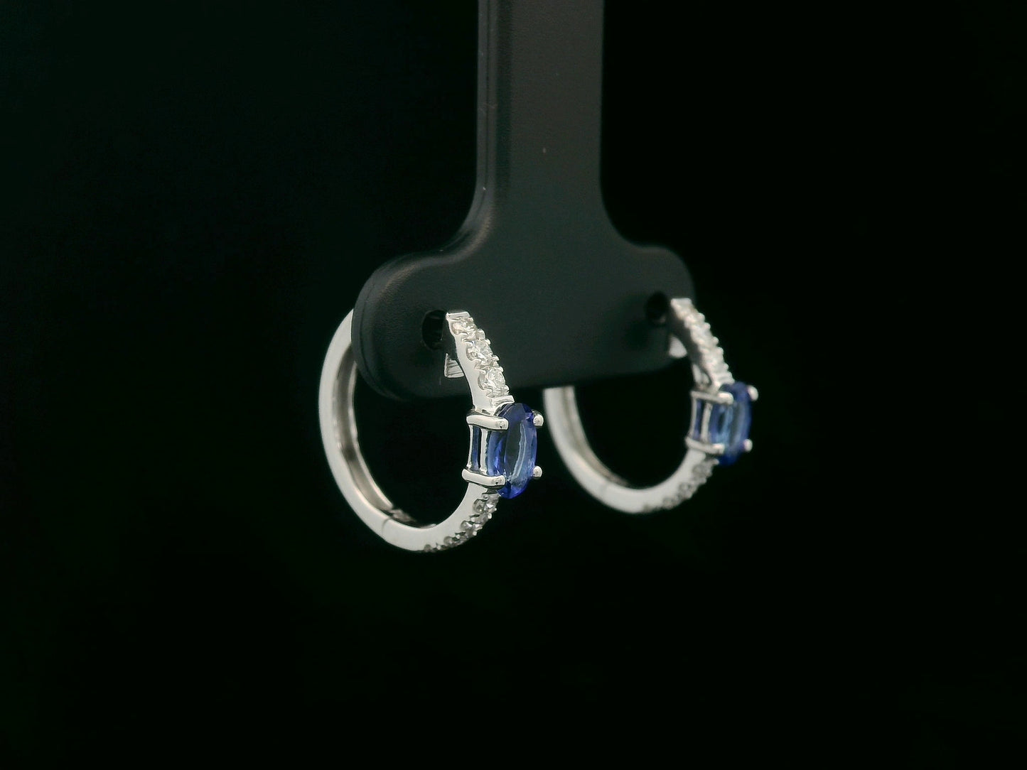 18K white gold hoop earrings featuring 0.44ct oval-cut tanzanites with 0.19ct pavé diamonds along the front curve of each hoop.