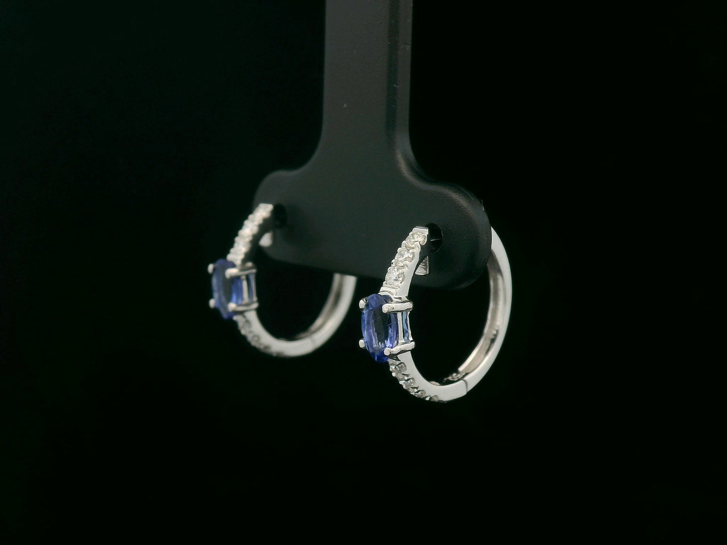 18K white gold hoop earrings featuring 0.44ct oval-cut tanzanites with 0.19ct pavé diamonds along the front curve of each hoop.