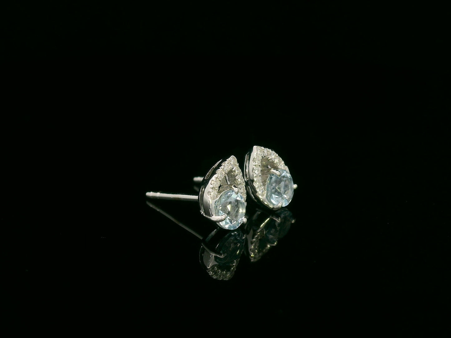 18K white gold earrings featuring 0.49ct round-cut aquamarine with 0.08ct diamond teardrop accent on one side of each stone.