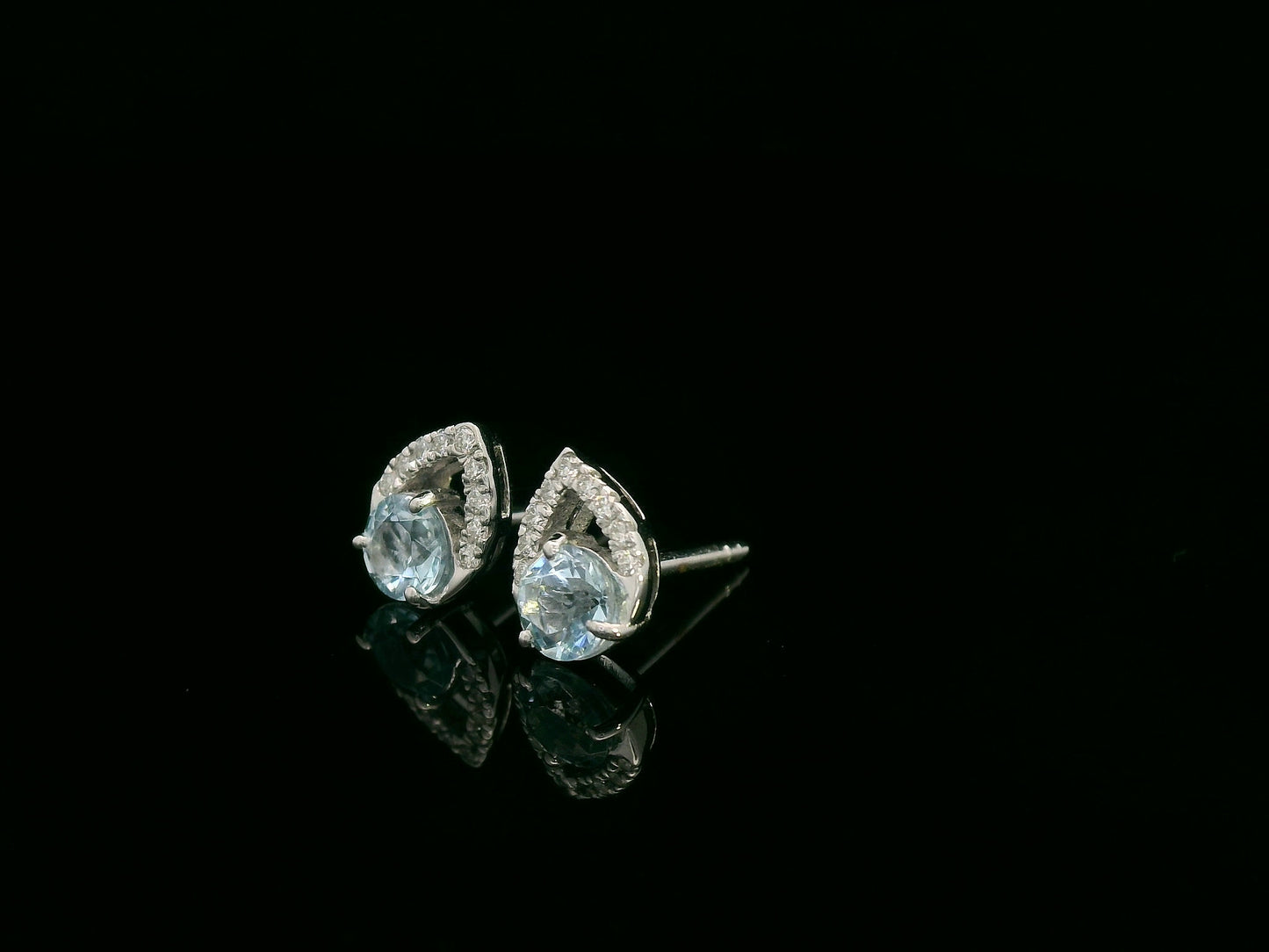 18K white gold earrings featuring 0.49ct round-cut aquamarine with 0.08ct diamond teardrop accent on one side of each stone.