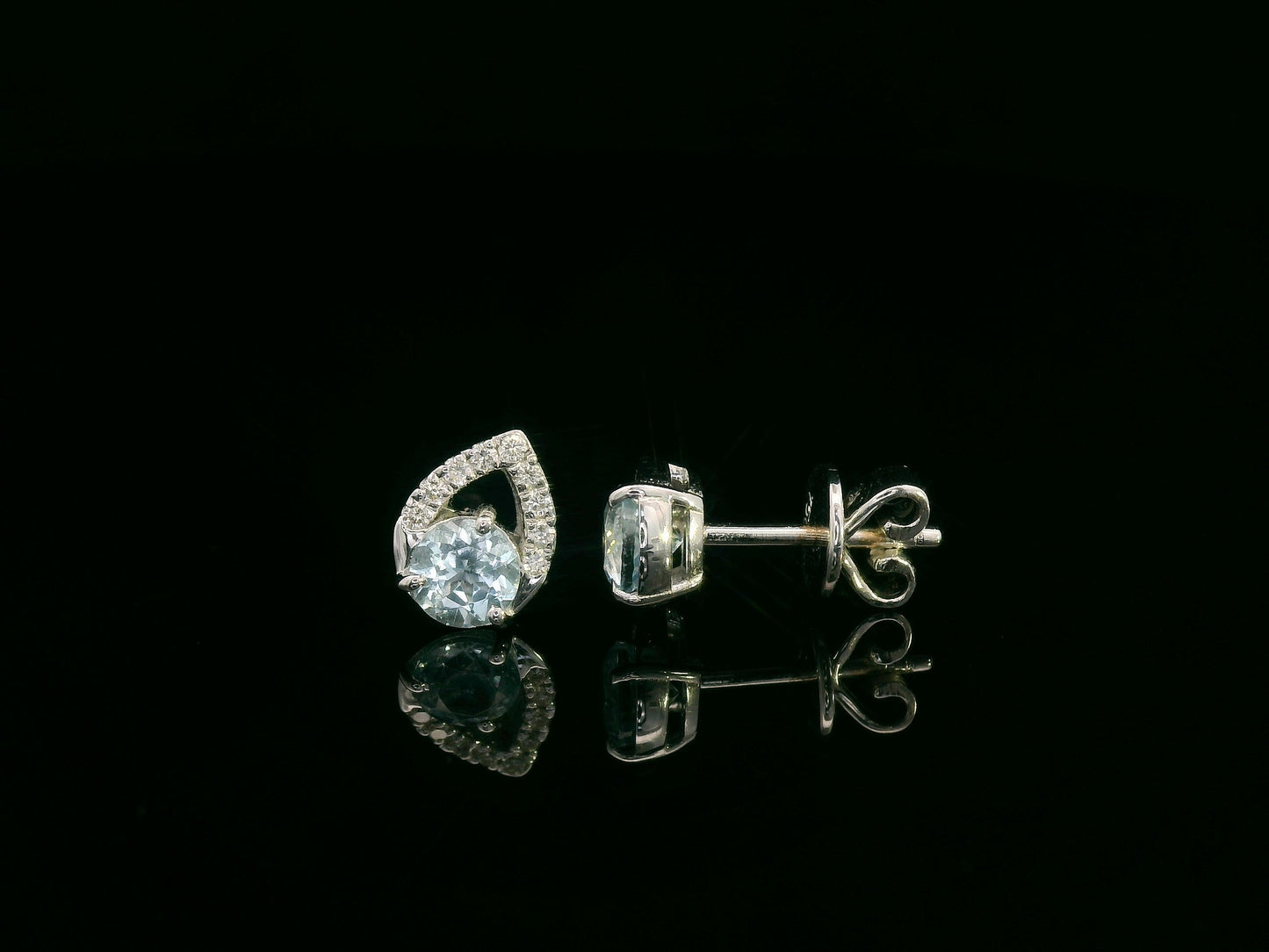 18K white gold earrings featuring 0.49ct round-cut aquamarine with 0.08ct diamond teardrop accent on one side of each stone.