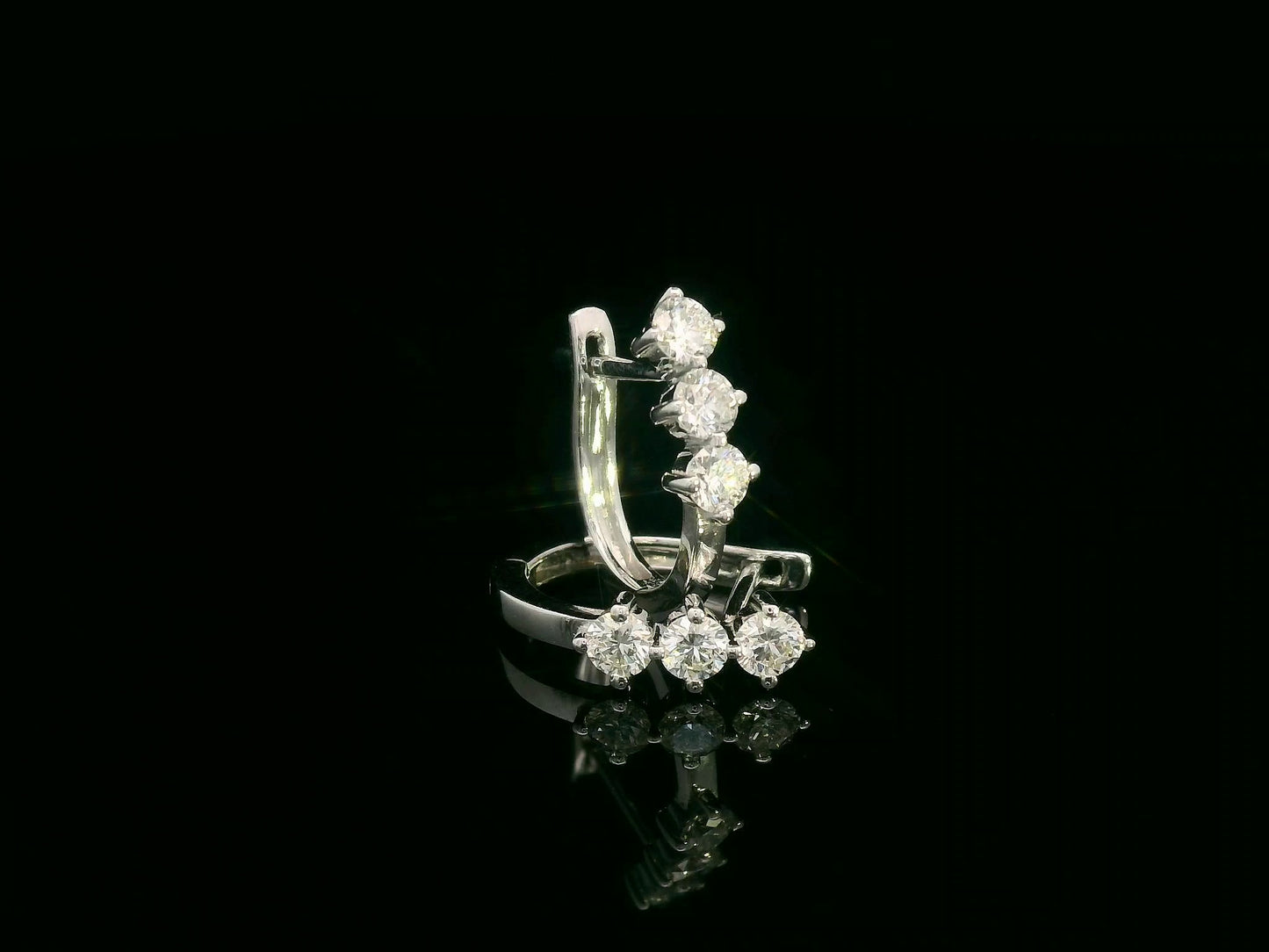 18K white gold huggie hoop earrings featuring three round brilliant-cut diamonds along the front, totaling 0.57 carat.