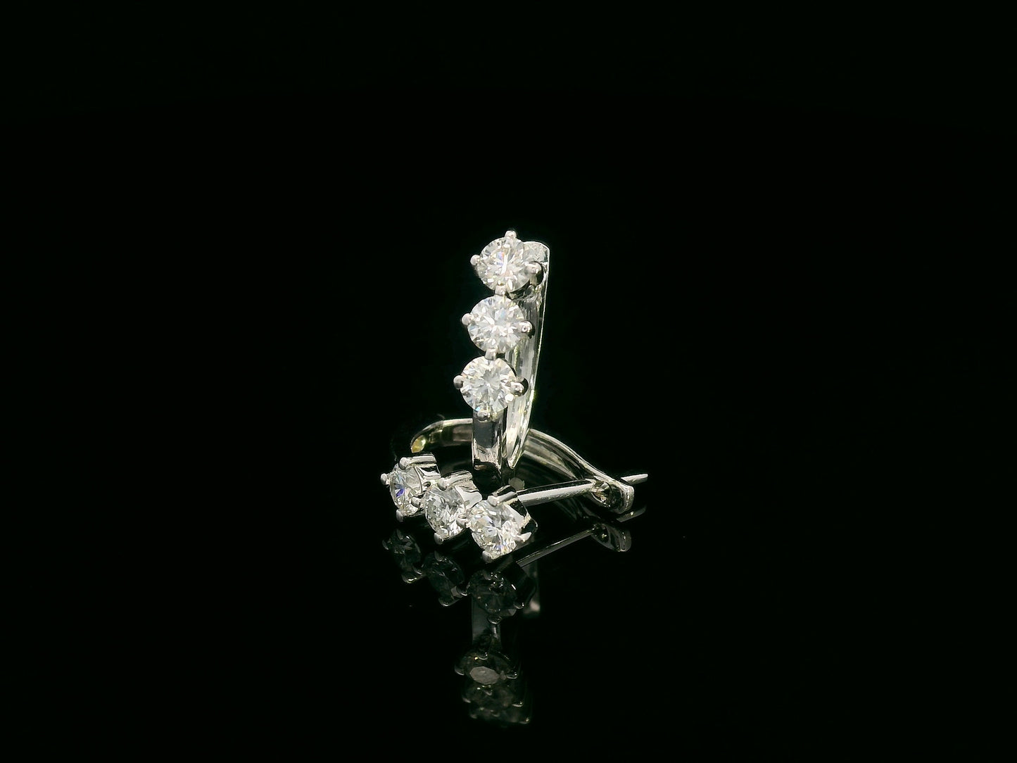 18K white gold huggie hoop earrings featuring three round brilliant-cut diamonds along the front, totaling 0.57 carat.