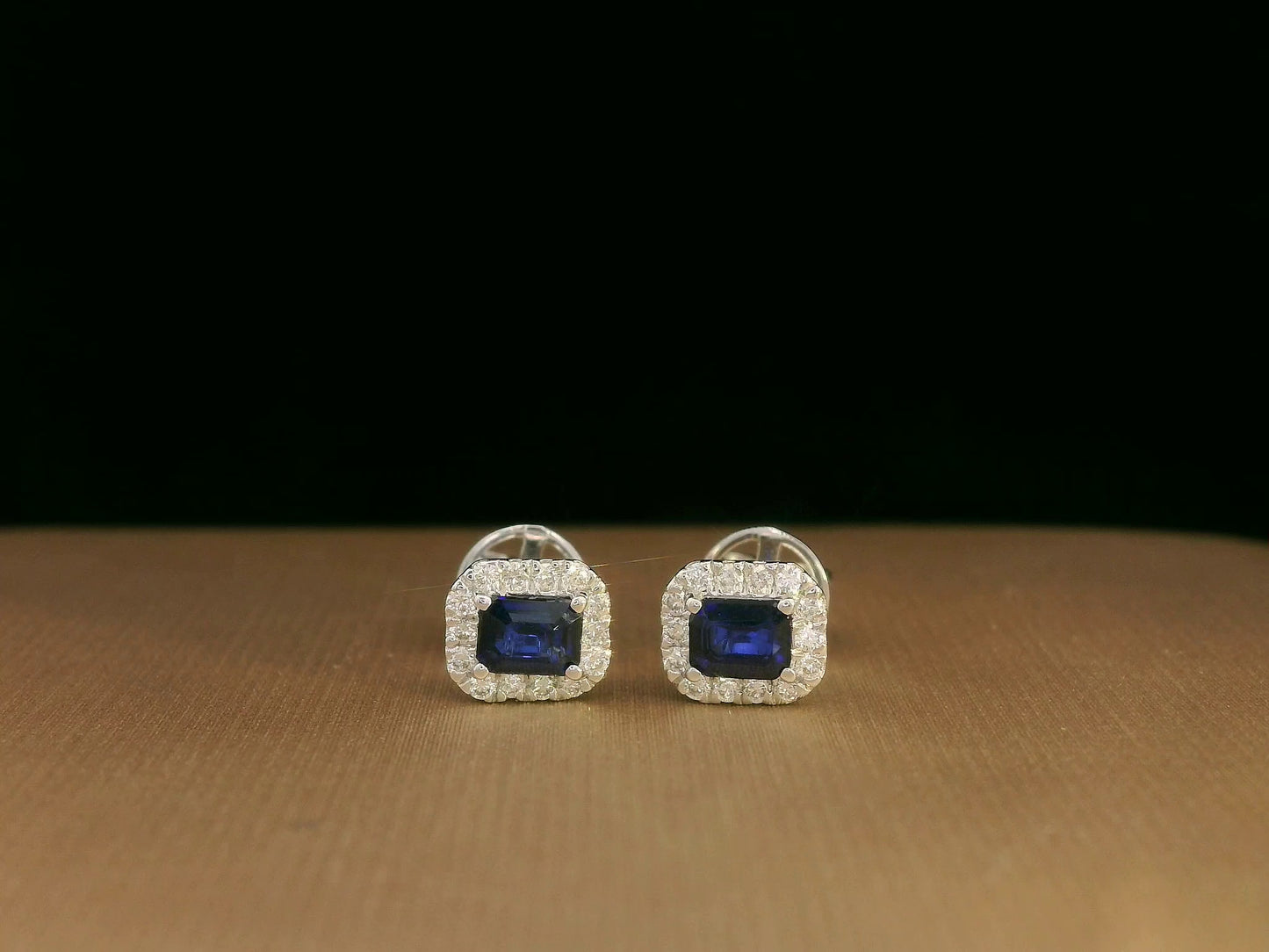 Minimalist 18K white gold halo stud earrings with emerald-cut blue sapphires and diamond accents
