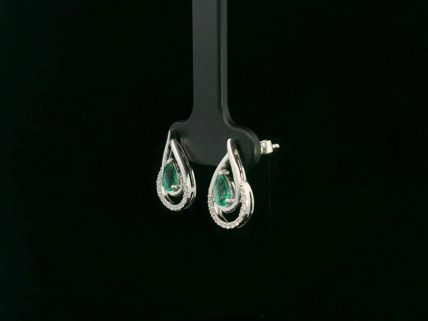 Emerald and diamond stud earrings in 18K white gold with pear-cut emeralds and pavé diamond accents by Emirates Diamonds