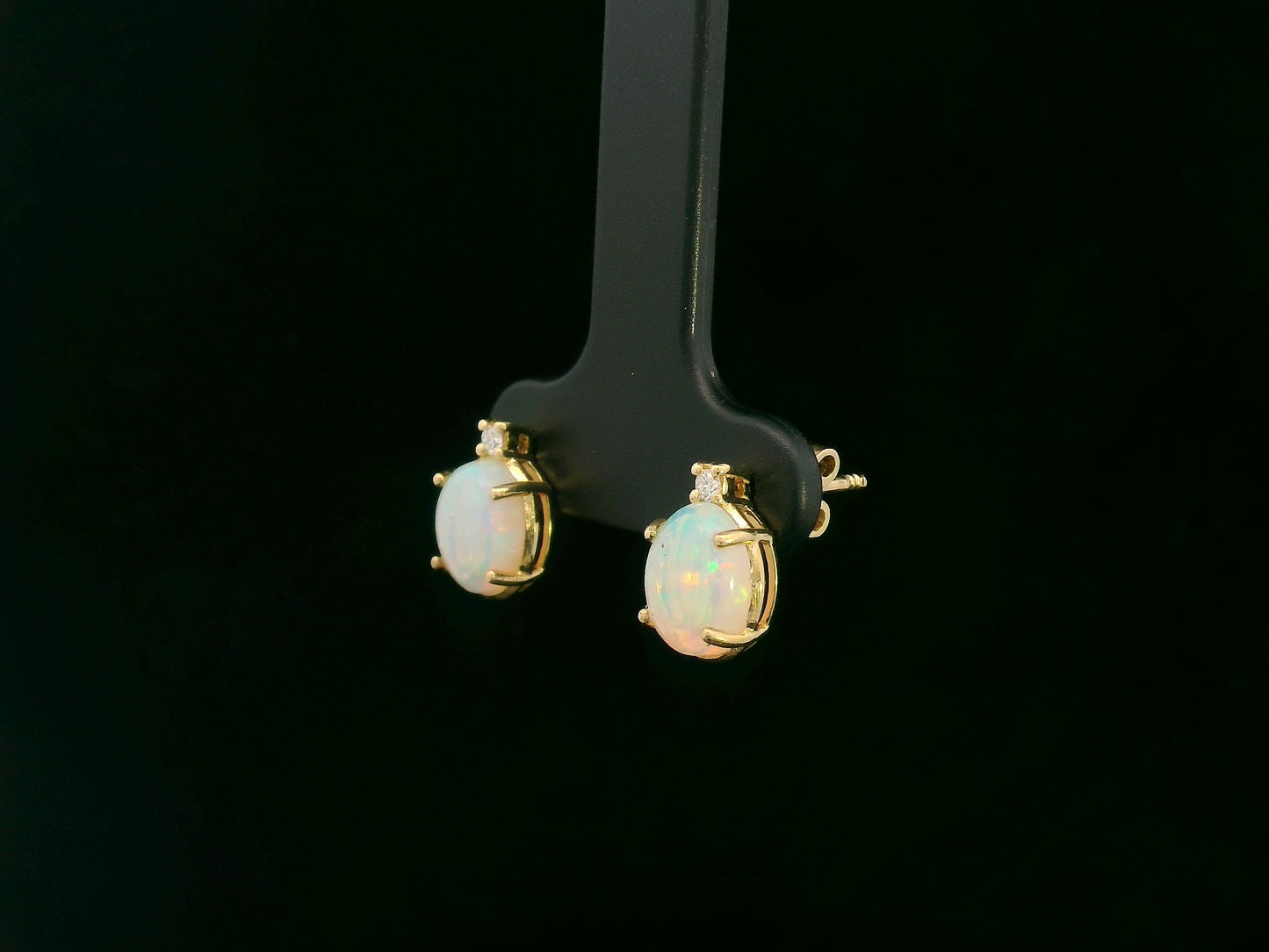 18K yellow gold opal and diamond stud earrings with oval opals and subtle diamond accents, luxury fine jewelry by Emirates Diamonds.